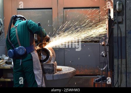 workers in safety clothing sanding a casting in an industrial company Stock Photo