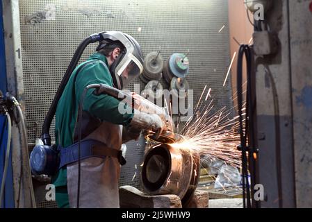 workers in safety clothing sanding a casting in an industrial company Stock Photo