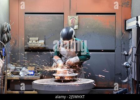 workers in safety clothing sanding a casting in an industrial company Stock Photo