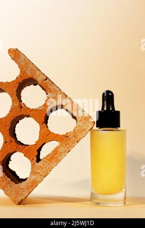 still life of cosmetic serum container with dropper next to red brick Stock Photo