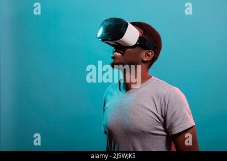 Modern guy using vr headset to play with 3d futuristic simulation in studio. Virtual reality goggles to enjoy visual innovation and interactive tech on headset. Millennial leisure Stock Photo