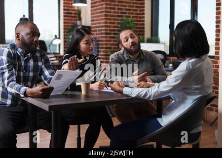 Multiethnic executive managers interviewing african american applicant discussing cv resume recruiting employer for human resources job in startup company office. Concept of hiring process Stock Photo