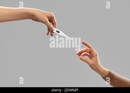 close up of hands giving each other thermometer Stock Photo