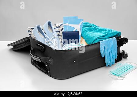 travel bag packed with clothes, gloves and masks Stock Photo