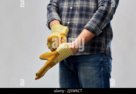 man or builder putting protective gloves on Stock Photo
