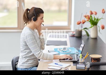 woman with headset and laptop working at home Stock Photo