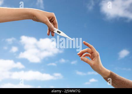 close up of hands giving each other thermometer Stock Photo