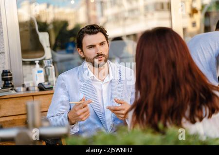 Young man and woman talking during business meeting at cafe outdoors Stock Photo