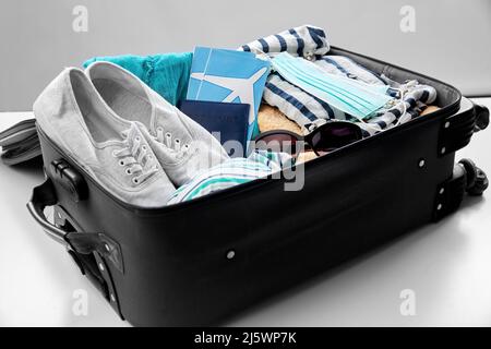 travel bag packed with clothes, tickets and masks Stock Photo