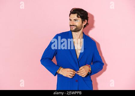 Young man wearing blue jacket smiling and looking aside isolated over pink background Stock Photo