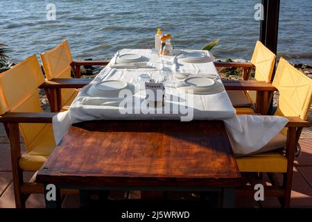 Served table in cafe by the sea with overturned plates and glasses on white tablecloth. Horizontal photo. Stock Photo