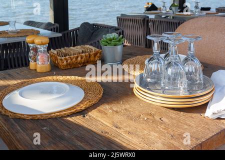 Wooden tables in cafe with overturned plates and glasses are waiting for guests. Horizontal photo. Stock Photo