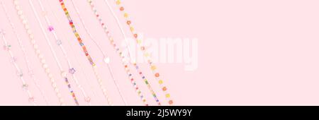 Banner with necklaces made from colorful beads and pearls on a pink background with place for text. Stock Photo