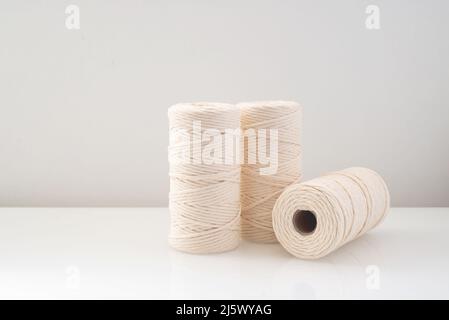 macrame threads wound bobbins of natural beige color are located on a light background Stock Photo