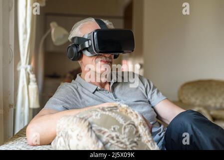 Senior man using VR glasses at home Stock Photo