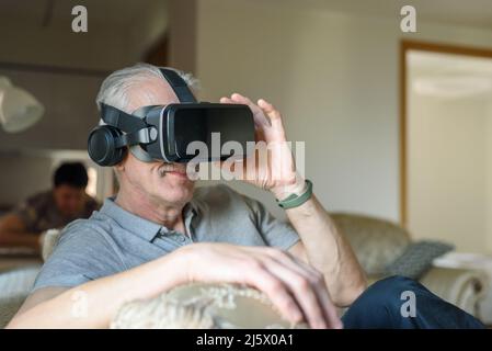 Senior man using VR glasses at home Stock Photo