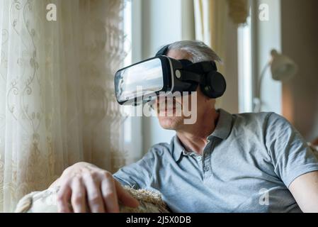 Senior man using VR glasses at home Stock Photo