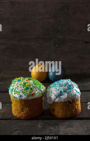 In the foreground there are 2 Easter cakes, in the back there are Painted eggs for Easter in the colors of the flag of Ukraine. Yellow and blue (cyan) Stock Photo