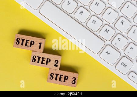 Step 1, 2 and 3 text on wooden blocks with keyboard. Stock Photo