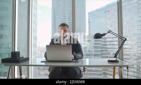 Quarantined businessman working remotely from his apartment. A businessman works remotely in his apartment. A businessman in a black suit lies on a so Stock Photo