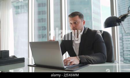 Focused serious businessman in suit thinking reading online news or solving business problem working on laptop looking at screen, worried puzzled exec Stock Photo