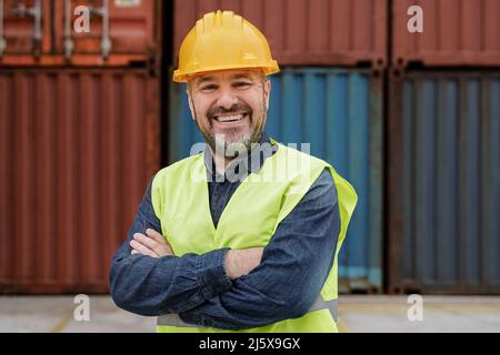 Happy senior man smiling at camera working at industrial shipping freight terminal port - Focus on face Stock Photo