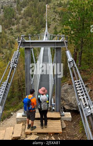Two hikers look at the only 65 centimeters wide stepping grid of the Charles Kuonen suspension bridge, Randa, Valais, Switzerland Stock Photo