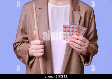 Woman teacher holding pills in hand on studio blue background, close-up Stock Photo