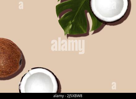Fresh and halved coconuts with monstera leaf on beige backdrop Stock Photo