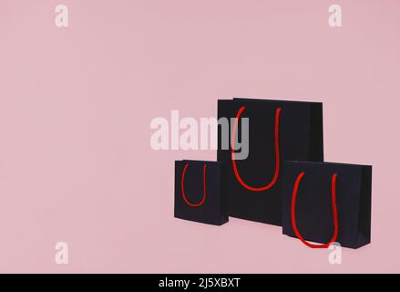 Three paper packs with red handles on pink backdrop Stock Photo