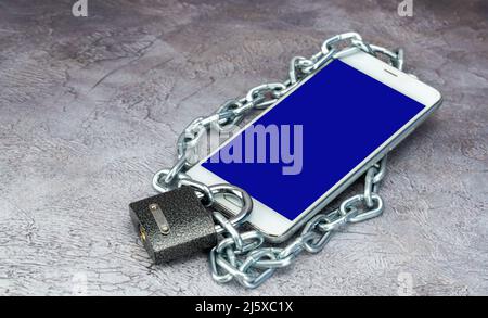 cell phone is locked. blocking social networks and mobile application. smartphone is covered with a chain and padlock.  Stock Photo