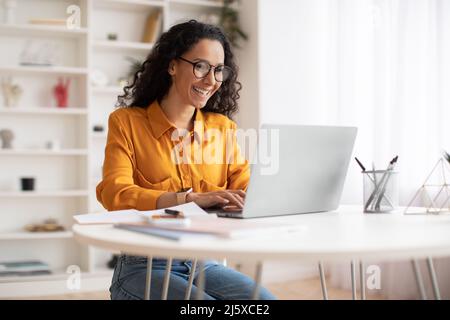 Happy Middle Eastern Businesswoman Using Laptop Sitting At Workplace Stock Photo