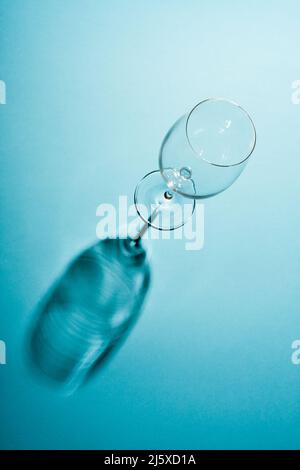 Empty wine glass with a creative shadow on blue background. Stock Photo