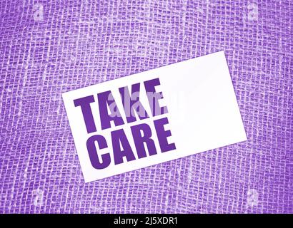 words Take care on card on burlap canvas. healthcare or business lifestyle concept. Stock Photo