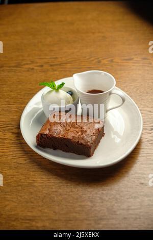 Chocolate cakes on a wooden table with ice cream and mint leaf on top, restaurant menu Stock Photo