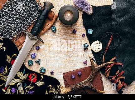 Fantasy role play board game concept. Frame decorated with various character objects tools with copy space. Dagger, chain mail, amulet, clothing, dice Stock Photo