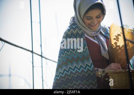 Happy young Muslim woman in headscarf looking down Stock Photo