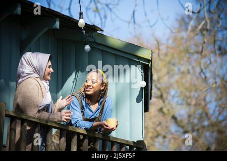 Young women friends with coffee talking on balcony Stock Photo