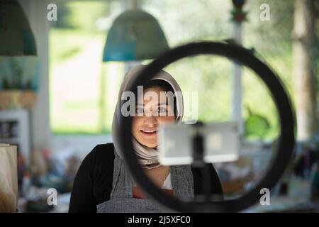 Young female influencer in hijab recording in artist studio Stock Photo