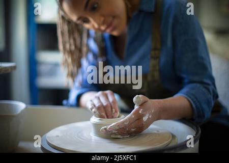 Young woman at pottery wheel in art studio Stock Photo