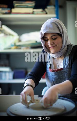 Young Muslim woman in hijab at pottery wheel Stock Photo