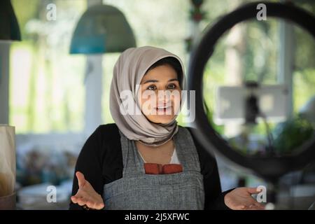 Young female influencer in hijab vlogging in studio Stock Photo