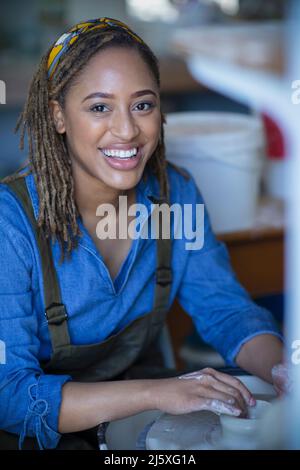 Portrait happy young female artist at pottery wheel Stock Photo