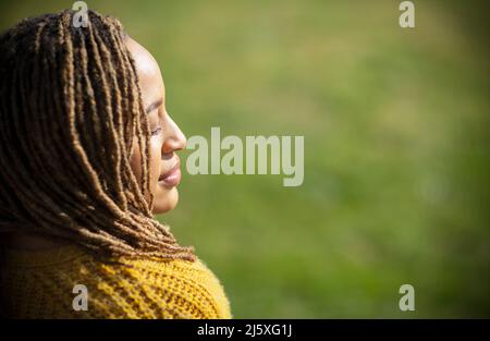 Serene young woman basking in sunlight with eyes closed Stock Photo