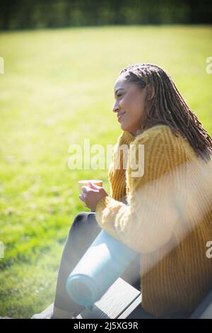 Serene young woman with yoga mat and coffee on sunny patio Stock Photo