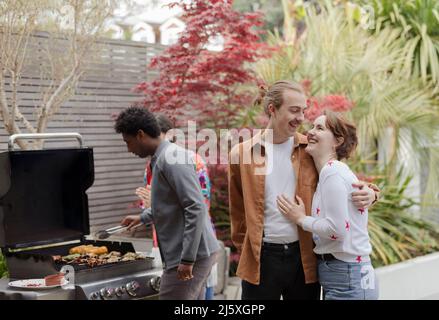 Happy young couple enjoying patio barbecue with friends Stock Photo