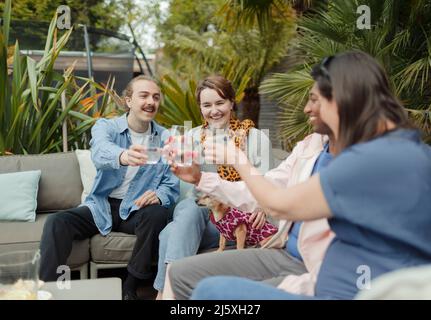 Happy couple friends toasting glasses on patio Stock Photo