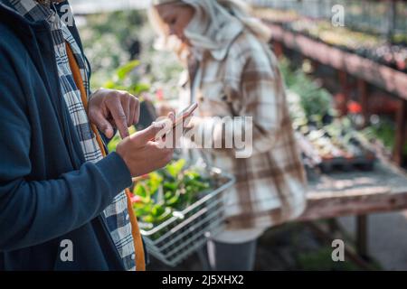 Customer with smart phone shopping in plant nursery Stock Photo