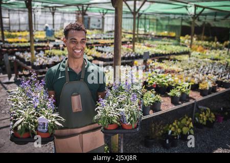 Happy male garden shop owner with trays of potted flowers Stock Photo