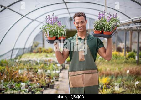 Portrait smiling male plant nursery worker with flowers in greenhouse Stock Photo